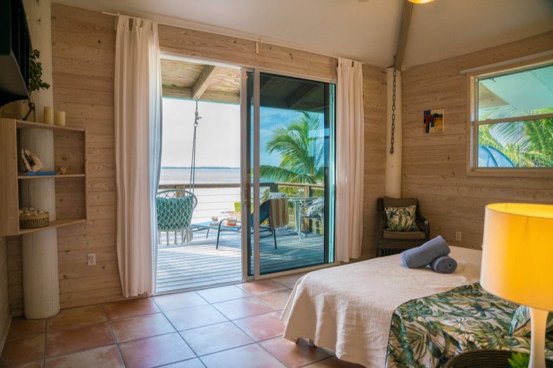 Master bedroom opening through sliding doors onto the deck, the sea framed in the doorway