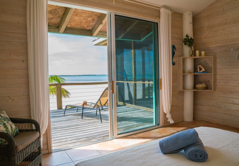 View from the bed through wide sliding doors to the deck and the sea horizon