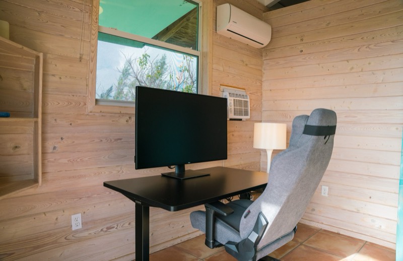 Office nook with sit-stand desk and 42-inch display, a window of dense tropical green
